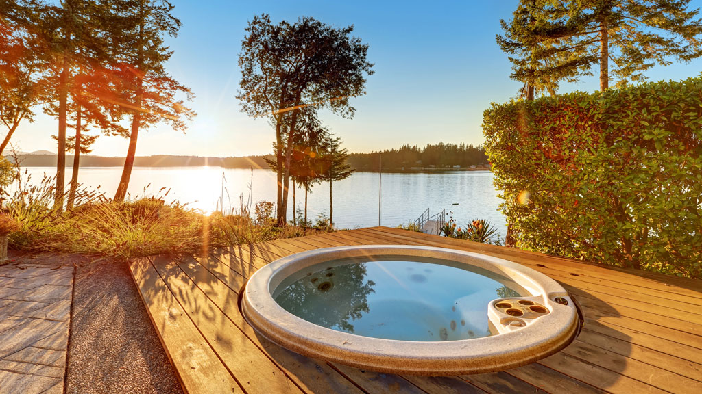 Personne montrant l'implantation prévue d'un spa avec des piquets au sol dans un jardin
