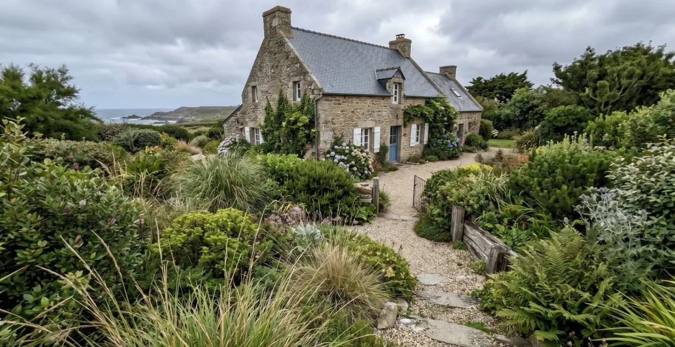 Jardin côtier breton luxuriant avec végétation dense adaptée au climat océanique, maison traditionnelle en pierre et ardoise en arrière-plan